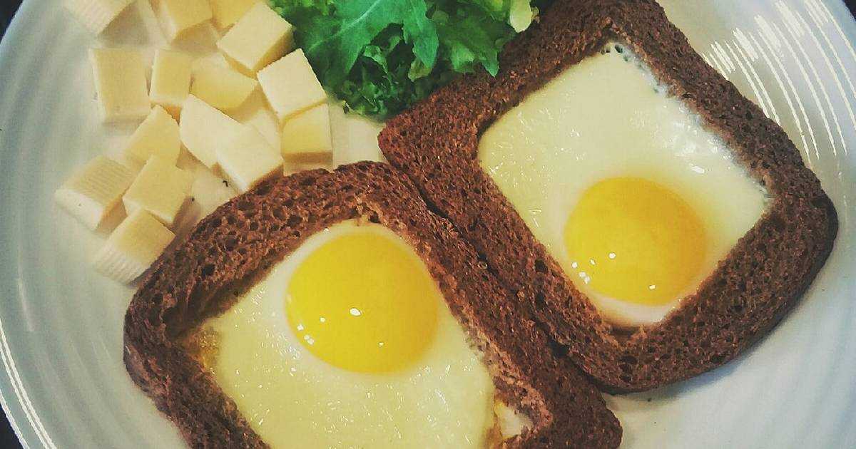 Необычная яичница в булочке или батоне на сковороде. яичница с колбасой и сыром, зажаренная в хлебе на сковороде жареные яйца в хлебе или оригинальный бутерброд
